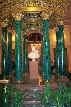 a statue in the center of a room with green columns