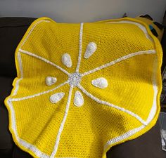 a yellow crocheted blanket sitting on top of a couch