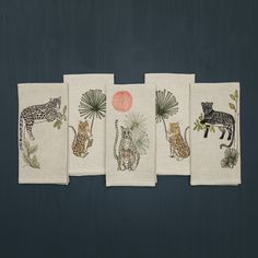 four tea towels with different animal designs on them, each featuring an image of a giraffe and two leopards