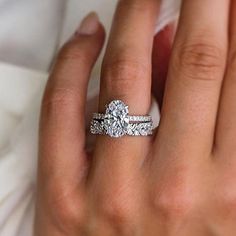 a woman's hand with two engagement rings on her finger and the ring has a diamond in it