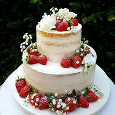 a three tiered cake with strawberries and flowers on top