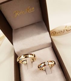 two gold rings in a box on a table