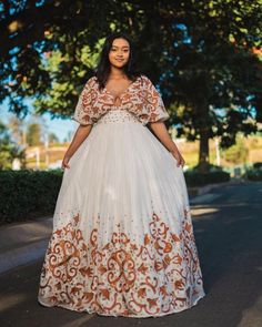 This Habesha dress is made of luxurious Menen fabric, known for its softness and durability. The dress features a gorgeous pattern of intricate Tilf embroidery, covering the entire dress from the neckline to the bottom. The Tilf embroidery adds a touch of elegance and sophistication to the dress, featuring delicate patterns and designs that are unique to Ethiopian traditional clothing. The dress is designed with a fitted bodice that accentuates the waistline and flares out into a flowing skirt, Modern Habesha Dress, Eritrean Dress, Habesha Dress, Habesha Kemis, Flowing Skirt, Traditional Clothing, Fitted Bodice, Traditional Outfits, Bridal Dresses