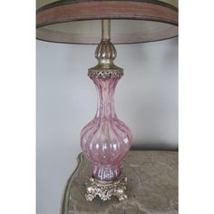 a pink glass lamp sitting on top of a table next to a light fixture with a metal base