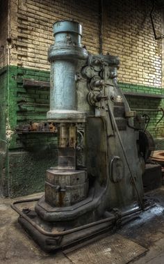 an old machine is sitting in the middle of a room with green bricks on the wall