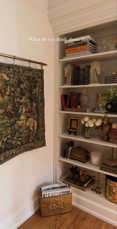 a tapestry hanging on the wall next to a bookshelf filled with books and other items