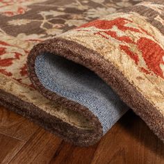 an area rug on the floor with wood floors and red, brown, beige and blue colors