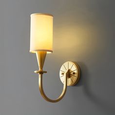 a wall light with a white shade on it's side and a gray wall in the background