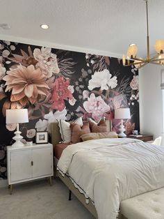 a bedroom with floral wallpaper and white bedding