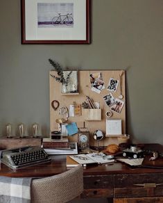 a desk with a typewriter, keyboard and pictures on the wall next to it