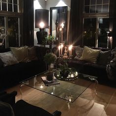 a living room filled with lots of furniture and candles in the middle of it's windows