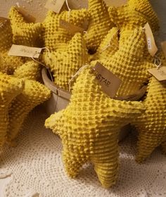 several yellow stuffed animals with tags attached to them sitting on a white doily covered table