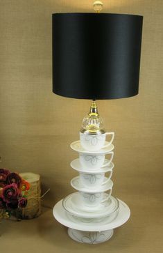 a lamp that is sitting next to a stack of cups and saucers on a table