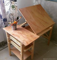 a wooden desk with an easel and paintbrushes in it