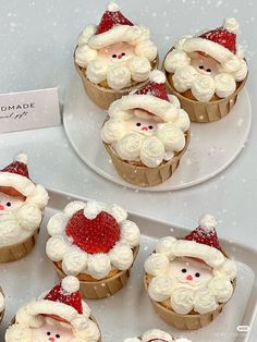 cupcakes decorated with santa claus's faces and snow flakes are on display