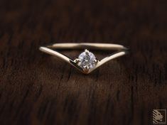 a close up of a diamond ring on a wooden table with dark wood grained background