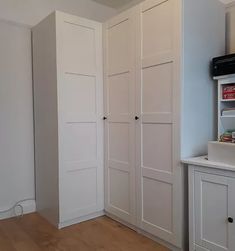 an empty room with white cupboards and wood flooring on the walls, along with a microwave oven