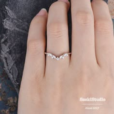 a woman's hand with a diamond ring on top of her left hand, next to a rock