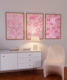 a white chair sitting next to a table with a lamp on it in front of two paintings