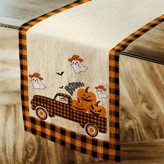 an orange and black plaid table runner with pumpkins, ghost's on the truck