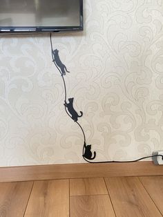 a tv mounted to the side of a wall next to a cat on a string