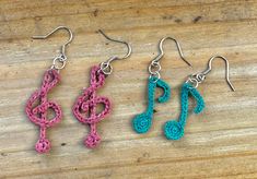 two crocheted earrings with musical notes hanging from them on a wooden table top