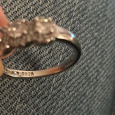 a person is holding a ring that has been made with silver beads and sits on a couch