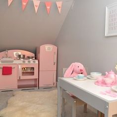 a small child's playroom with pink furniture and accessories