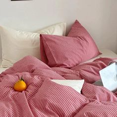 a red and white striped comforter on top of a bed next to a pillow