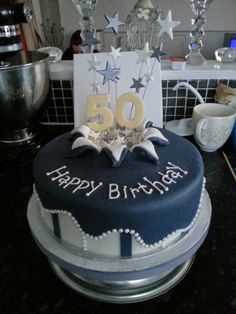 a blue birthday cake with white stars and the number 50 on it's top