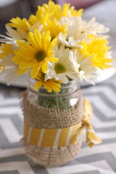 yellow and white flowers in a mason jar with burlap ribbon around the bottom