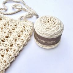 a white crochet bag next to a ball of yarn