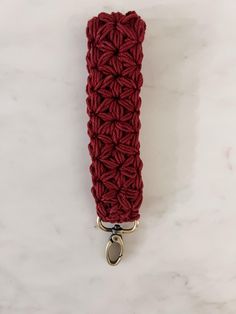 a red crochet key fobring on a white marble surface with a metal hook