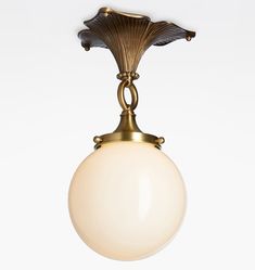 an antique style light fixture with a white glass ball hanging from it's center