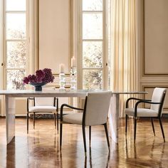 a dining room table with chairs and a vase filled with flowers on top of it