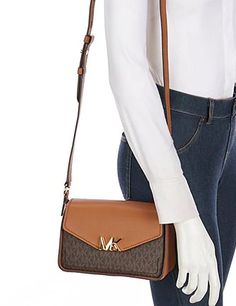 A chic silhouette accented with an MK logo, the Sylvia messengeris a petite way to carry your essentials.Small sized bag; 8-1/4"W x 5-1/2"H x 3-1/2"D (width is measured across the bottom of handbag)24-1/2"L adjustable strapFlap with magnetic closureGold-tone hardwareInterior back zip pocket & front slip pocketColor: Brown Travel Shoulder Bag With Logo And Flap, Logo Flap Shoulder Bag For Travel, Travel Shoulder Bag With Flap And Logo, Everyday Flap Bag With Logo, Logo Crossbody Satchel For Travel, Small Messenger Bag, Mk Logo, Messenger Bag, Zip Pockets