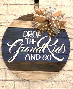 a wooden sign that says drop the grand kids and go hanging on a brick wall