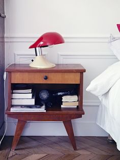 a nightstand with a lamp on top of it next to a bed