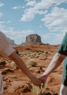 two people holding hands while walking through the desert