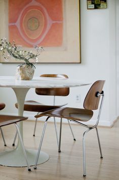 an image of a table and chairs in a room with pictures on the wall behind it