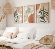 a living room filled with white furniture and paintings on the wall above it's couch