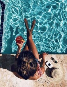 a woman laying on the ground in front of a swimming pool with her feet up