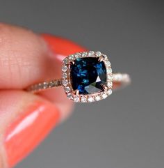 a woman's hand holding an engagement ring with a blue diamond in the center