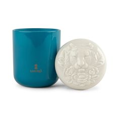 a blue cup with a white lion head on it next to a teal mug