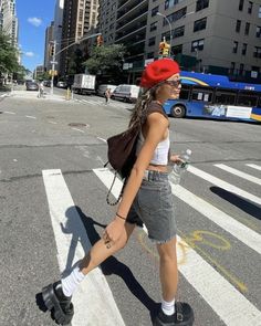 a woman walking across a street in the middle of a crosswalk with buildings behind her