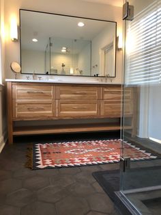 a bathroom with a large mirror, sink and rug on the floor in front of it