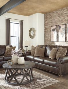 a living room with two couches and a coffee table in front of a brick wall