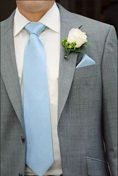 a man in a gray suit with a blue tie and white rose boutonniere