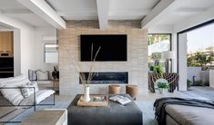 a living room with couches, tables and a television mounted on the wall above it