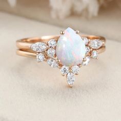 an opal and diamond ring is shown on top of a piece of cloth with flowers in the background